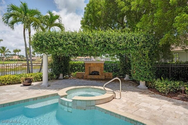 2366 Alexander Palm Dr, Naples, FL 34105 - view of swimming pool featuring exterior fireplace, a patio, a pool with connected hot tub, and a water view