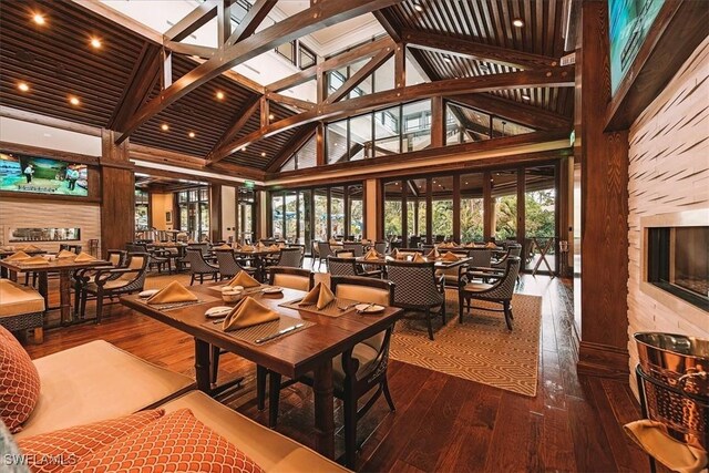 2366 Alexander Palm Dr, Naples, FL 34105 - dining area featuring high vaulted ceiling, wood-type flooring, beamed ceiling, and a fireplace