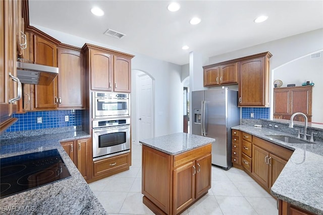 1128 NW 43rd Ave, Cape Coral, FL 33993 - kitchen featuring appliances with stainless steel finishes, a sink, under cabinet range hood, arched walkways, and light stone countertops