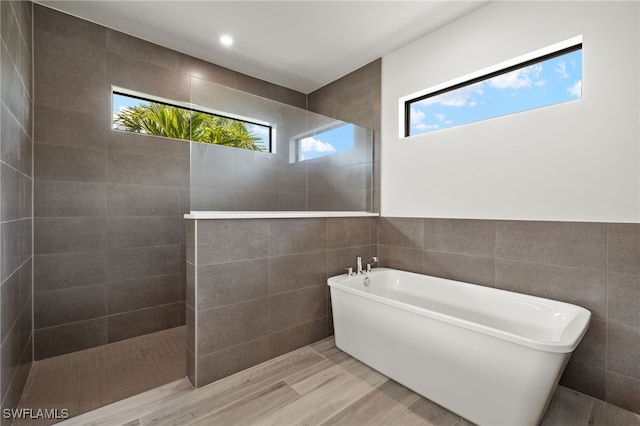 2110 SW 52nd Ter, Cape Coral, FL 33914 - bathroom with tile walls, a freestanding tub, a walk in shower, and wood finished floors