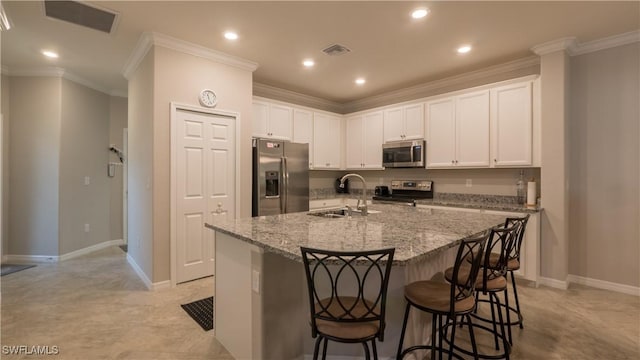 9076 Glenforest Dr, Naples, FL 34120 - kitchen featuring appliances with stainless steel finishes, a sink, a kitchen bar, white cabinetry, and light stone counters