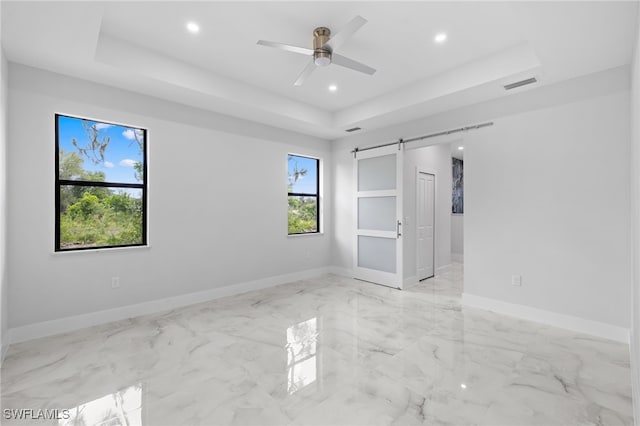 2513 13th St SW, Lehigh Acres, FL 33976 - unfurnished bedroom featuring a tray ceiling, a barn door, recessed lighting, baseboards, and a ceiling fan