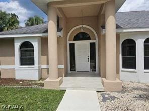 718 Jefferson Ave, Lehigh Acres, FL 33936 - property entrance featuring stucco siding and roof with shingles