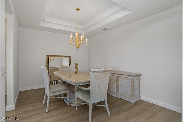 23560 Wisteria Pointe Dr Unit 506, Estero, FL 34135 - dining area featuring a chandelier, a raised ceiling, light wood-type flooring, and baseboards