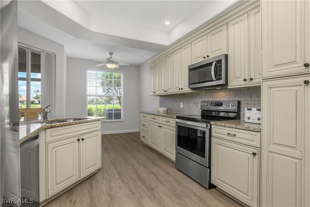 23560 Wisteria Pointe Dr Unit 506, Estero, FL 34135 - kitchen featuring appliances with stainless steel finishes, a sink, cream cabinetry, light wood finished floors, and baseboards