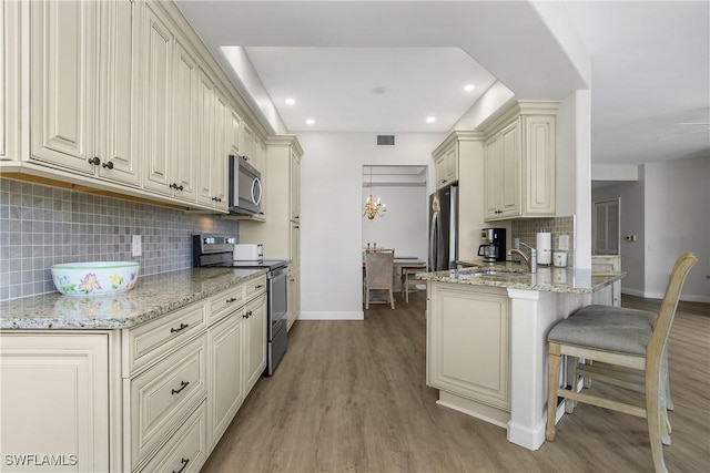 23560 Wisteria Pointe Dr Unit 506, Estero, FL 34135 - kitchen featuring stainless steel appliances, baseboards, a sink, a peninsula, and a kitchen bar
