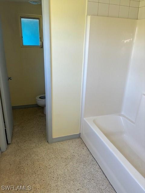 1610 Woodlawn Ave, Punta Gorda, FL 33950 - bathroom with toilet, carpet floors, baseboards, washtub / shower combination, and speckle patterned floor
