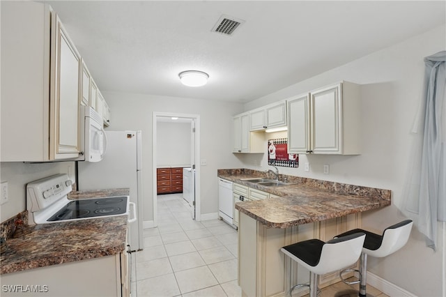 426 Chestnut Ave NW, Port Charlotte, FL 33952 - kitchen featuring a sink, white appliances, a kitchen breakfast bar, a peninsula, and dark countertops