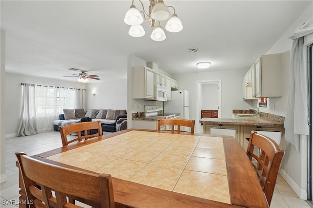 426 Chestnut Ave NW, Port Charlotte, FL 33952 - dining room with light tile patterned flooring, a chandelier, a ceiling fan, and baseboards