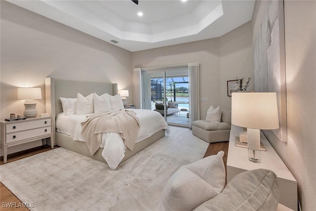 917 Tierra Lago Way, Naples, FL 34119 - bedroom featuring access to exterior, a tray ceiling, and wood finished floors
