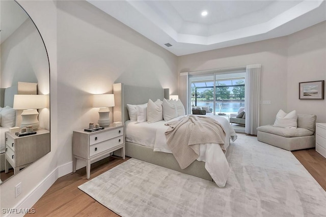 917 Tierra Lago Way, Naples, FL 34119 - bedroom featuring a tray ceiling, wood finished floors, access to exterior, a water view, and recessed lighting
