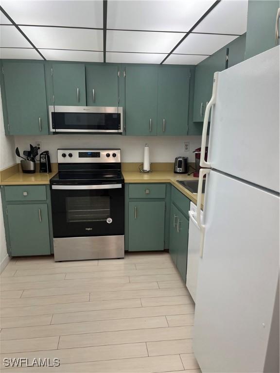1740 Pine Valley Dr Unit 205, Fort Myers, FL 33907 - kitchen with stainless steel appliances, light countertops, green cabinets, light wood-type flooring, and a drop ceiling