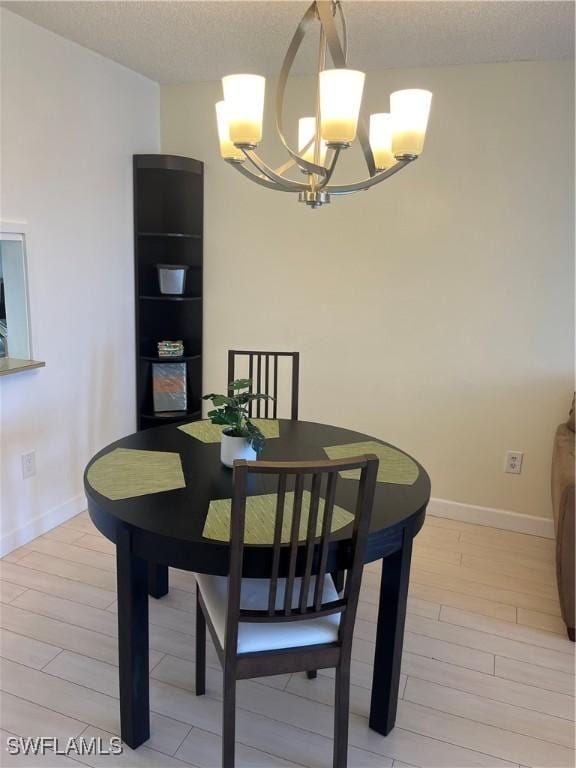 1740 Pine Valley Dr Unit 205, Fort Myers, FL 33907 - dining room featuring a chandelier, light wood finished floors, baseboards, and a textured ceiling