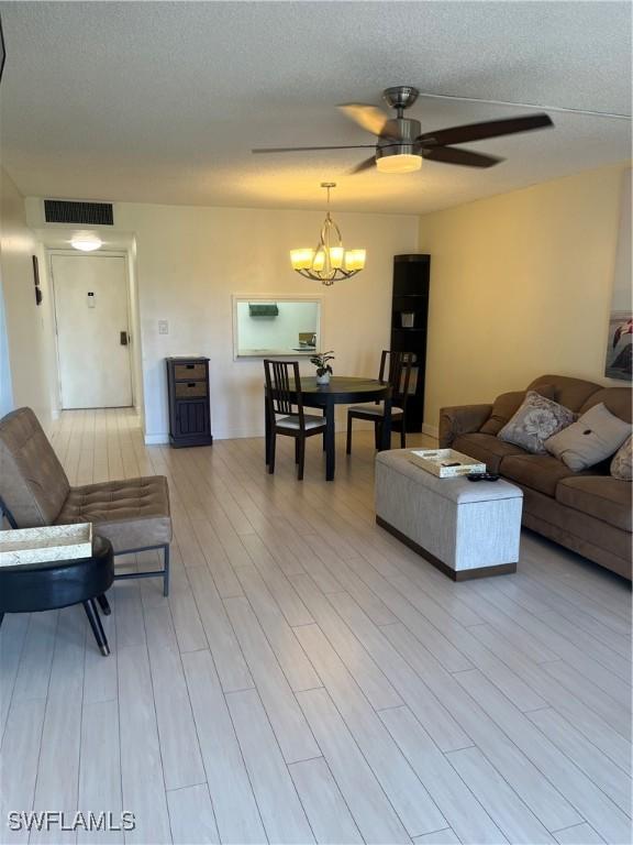 1740 Pine Valley Dr Unit 205, Fort Myers, FL 33907 - living room featuring ceiling fan, light wood-style flooring, a chandelier, and a textured ceiling