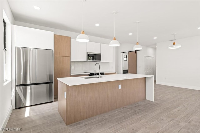 3203 18th St W, Lehigh Acres, FL 33971 - kitchen featuring appliances with stainless steel finishes, an island with sink, light countertops, white cabinets, and a barn door