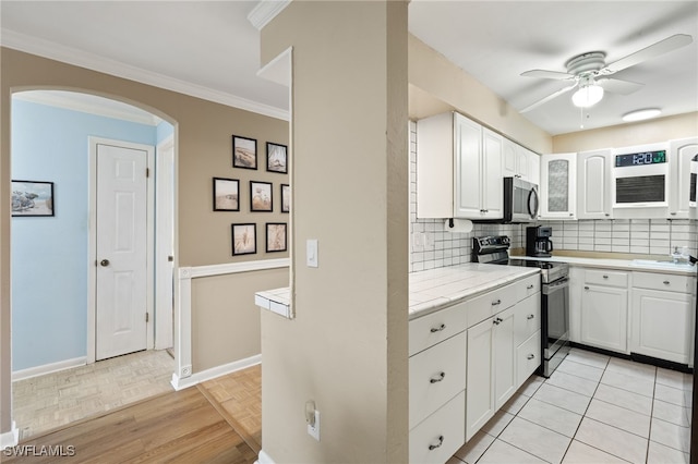 909 SE 46th Ln Unit 104, Cape Coral, FL 33904 - kitchen featuring electric range oven, stainless steel microwave, a ceiling fan, arched walkways, and light countertops