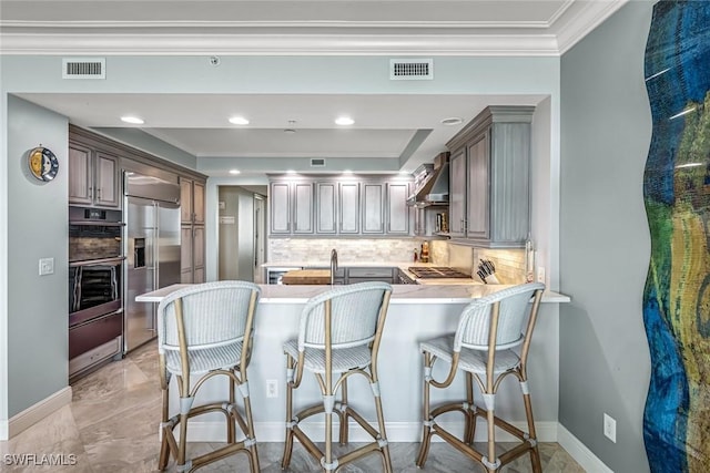 275 Indies Way Unit 1603, Naples, FL 34110 - kitchen with appliances with stainless steel finishes, crown molding, decorative backsplash, a peninsula, and wall chimney range hood
