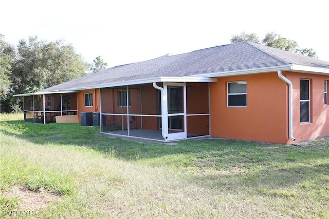 4526/4524 28th St SW, Lehigh Acres, FL 33973 - rear view of house featuring a sunroom, central AC unit, roof with shingles, a lawn, and stucco siding