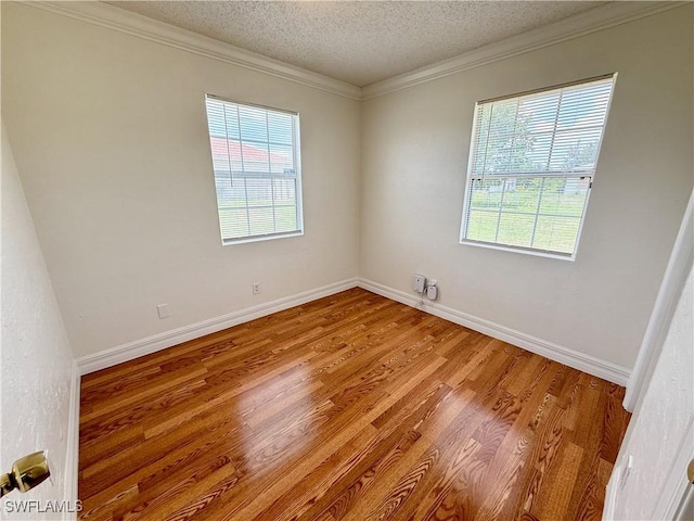 3700 26th St SW, Lehigh Acres, FL 33976 - empty room with plenty of natural light, wood finished floors, crown molding, baseboards, and a textured ceiling