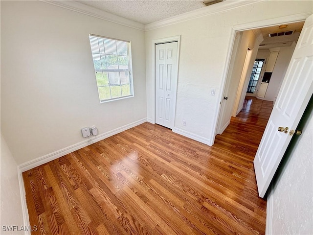 3700 26th St SW, Lehigh Acres, FL 33976 - unfurnished bedroom featuring light wood-type flooring, a textured ceiling, a closet, baseboards, and crown molding