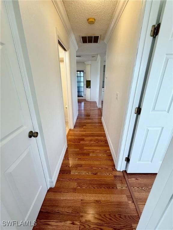 3700 26th St SW, Lehigh Acres, FL 33976 - hallway featuring a textured ceiling, light wood finished floors, and baseboards