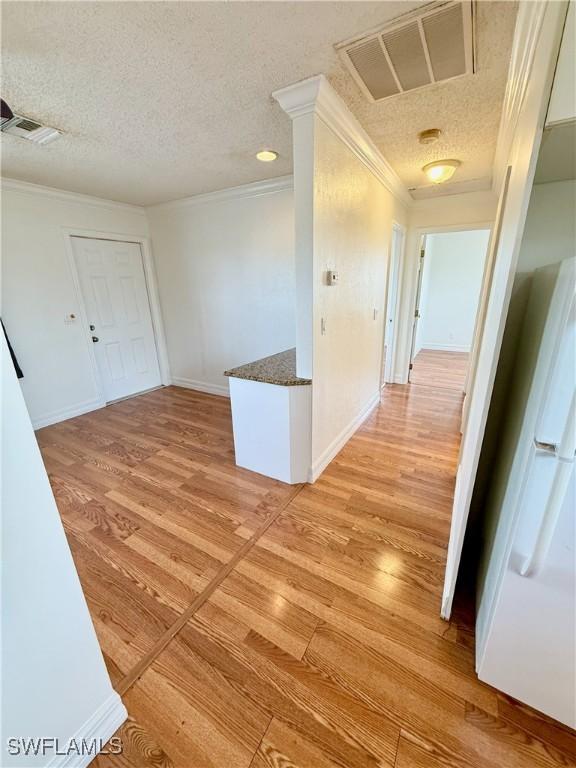 3700 26th St SW, Lehigh Acres, FL 33976 - corridor featuring light wood-style flooring, ornamental molding, a textured ceiling, and baseboards