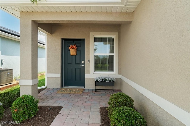 8833 Swell Brooks Ct, North Fort Myers, FL 33917 - doorway to property featuring stucco siding, central AC unit, and covered porch