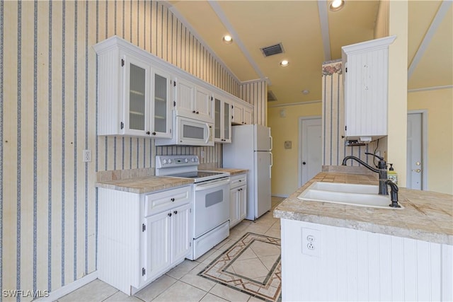9091 Cypress Dr N, Fort Myers, FL 33967 - kitchen featuring white appliances, a sink, light countertops, light tile patterned floors, and glass insert cabinets