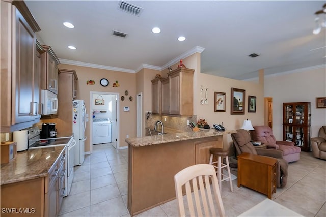 1115 Comet Ave, Labelle, FL 33935 - kitchen with white appliances, washer / dryer, a peninsula, light tile patterned floors, and open floor plan