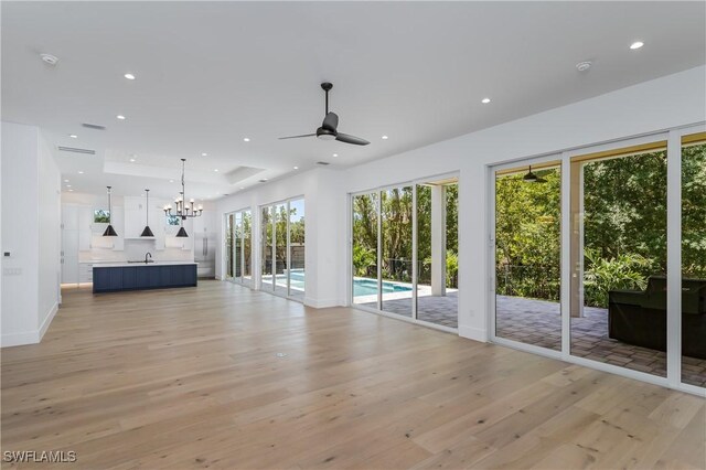2854 Coach House Way, Naples, FL 34105 - unfurnished living room featuring light wood finished floors, a ceiling fan, recessed lighting, a chandelier, and a sink