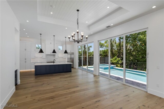 2854 Coach House Way, Naples, FL 34105 - kitchen featuring a raised ceiling, a sink, white cabinets, light countertops, and a chandelier