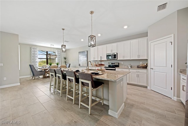 10700 Clementine Pl, North Fort Myers, FL 33917 - kitchen featuring appliances with stainless steel finishes, a center island with sink, a kitchen breakfast bar, recessed lighting, and white cabinetry