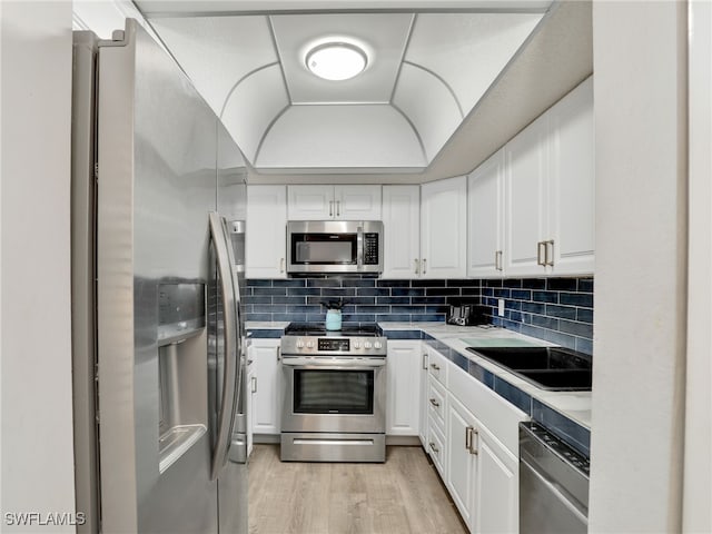 5479 Peppertree Dr Unit 13, Fort Myers, FL 33908 - kitchen with stainless steel appliances, white cabinets, light wood-type flooring, decorative backsplash, and a sink
