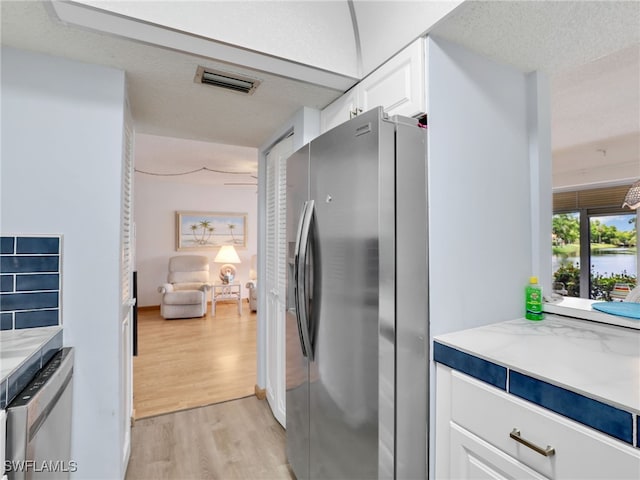 5479 Peppertree Dr Unit 13, Fort Myers, FL 33908 - kitchen featuring stainless steel appliances, light wood-style floors, white cabinets, and a textured ceiling