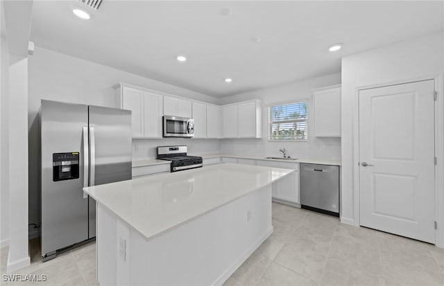 44225 Kelly Dr, Punta Gorda, FL 33982 - kitchen featuring stainless steel appliances, white cabinets, a sink, light countertops, and a center island