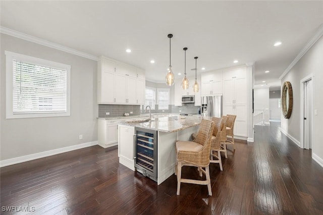 646 Vintage Reserve Cir Unit 4D, Naples, FL 34119 - kitchen featuring wine cooler, stainless steel appliances, a spacious island, white cabinets, and backsplash