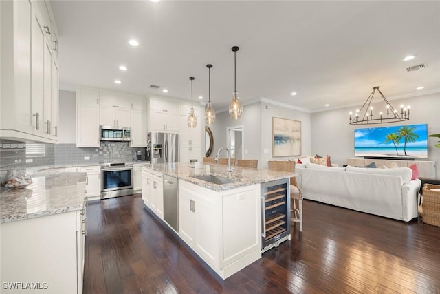 646 Vintage Reserve Cir Unit 4D, Naples, FL 34119 - kitchen with wine cooler, a sink, appliances with stainless steel finishes, open floor plan, and ornamental molding
