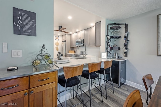 5741 Whitaker Rd Unit D103, Naples, FL 34112 - kitchen featuring a kitchen breakfast bar, appliances with stainless steel finishes, wood finished floors, a ceiling fan, and a sink