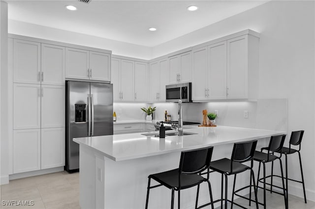 12467 Purple Ficus Way, Naples, FL 34120 - kitchen with appliances with stainless steel finishes, a peninsula, a breakfast bar area, light countertops, and recessed lighting