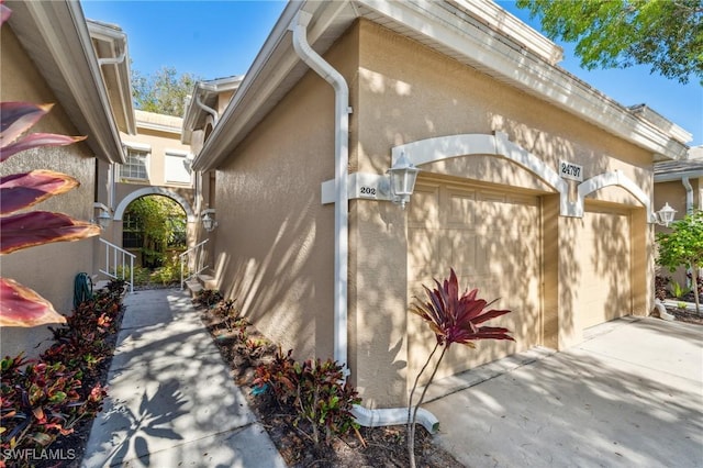 24797 Lakemont Cove Ln Unit 202, Bonita Springs, FL 34134 - view of home's exterior featuring stucco siding, concrete driveway, and an attached garage