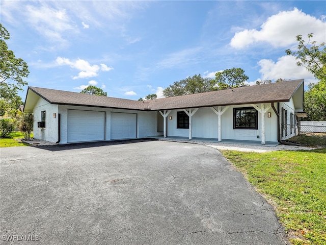 208 Erie Dr, Naples, FL 34110 - ranch-style house featuring an attached garage, asphalt driveway, and covered porch