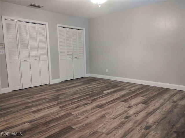 7821 Deni Dr, North Fort Myers, FL 33917 - unfurnished bedroom with multiple closets, dark wood-style flooring, and baseboards