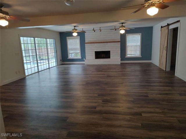 7821 Deni Dr, North Fort Myers, FL 33917 - unfurnished living room with a barn door, a ceiling fan, dark wood-style floors, and baseboards