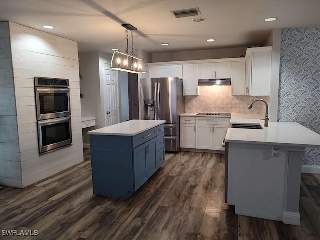 7821 Deni Dr, North Fort Myers, FL 33917 - kitchen with stainless steel appliances, dark wood-style floors, light countertops, white cabinetry, and under cabinet range hood