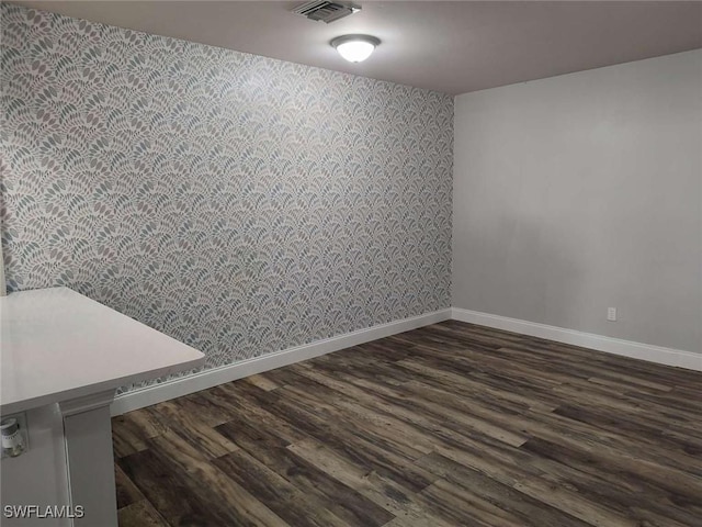 7821 Deni Dr, North Fort Myers, FL 33917 - unfurnished room featuring wallpapered walls, baseboards, an accent wall, and dark wood-type flooring