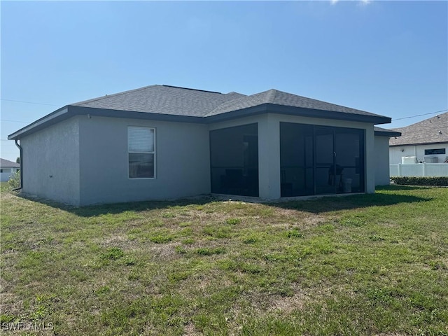 1818 NE 6th Pl, Cape Coral, FL 33909 - rear view of house with a sunroom, a lawn, stucco siding, and roof with shingles