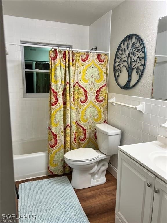 204 Flagler St, Clewiston, FL 33440 - full bath featuring toilet, wood finished floors, vanity, shower / bath combo, and tile walls