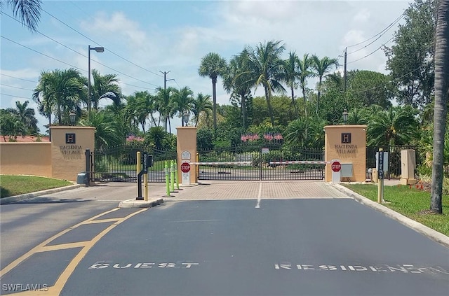 27910 Hacienda E Blvd Unit 201B, Bonita Springs, FL 34135 - view of asphalt street with traffic signs, a gate, curbs, a gated entry, and street lights