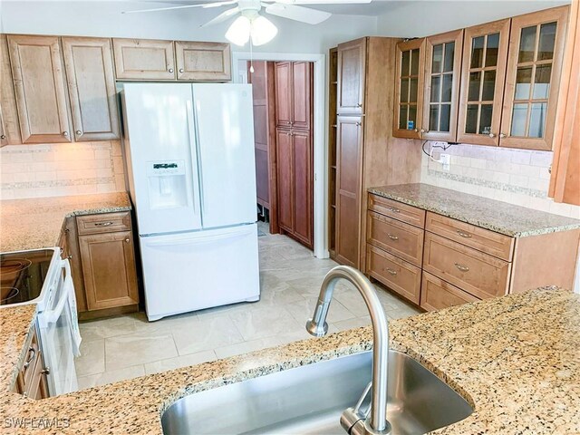 13511 Stratford Place Cir Unit 305, Fort Myers, FL 33919 - kitchen with white appliances, a sink, light stone counters, and decorative backsplash