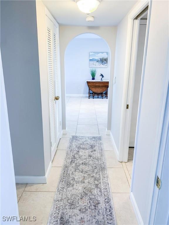 13511 Stratford Place Cir Unit 305, Fort Myers, FL 33919 - corridor featuring arched walkways, light tile patterned flooring, and baseboards